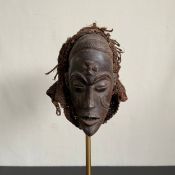 A Central African carved hardwood ceremonial Mwana Pwo or female mask mounted to a woven headdress