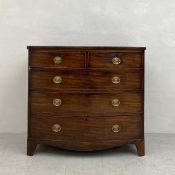 A Georgian mahogany bow-fronted chest of drawers having a shaped top above an arrangement of two