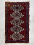 A hand knotted Qashqai rug having a central row of five stepped diamond lozenge medallions in