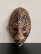 A 20th century carved African mask, possibly from Papua New Guinea, with pigment. L.27cm