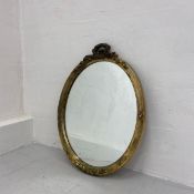 A 19th century wall mirror having an oval plate in a moulded gilt surround with a carved laurel