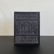 A mid 20th century black tea trade brick having a central press moulded image of a Chinese Paifang
