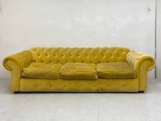 A 20th century three seater Chesterfield sofa having a scrolled deep button back and arms over a