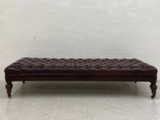 A large late 19th century ottoman or footstool having a deep buttoned brown leather seat raised on