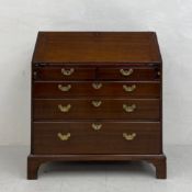A Georgian mahogany bureau having a fall front with a gilt and tooled red leather lined slope with a