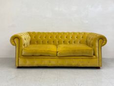 A 20th century two seater Chesterfield sofa having a scrolled deep button back and arms over a