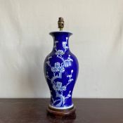 A Chinese blue and white prunus blossom baluster form porcelain table lamp raised on a circular
