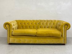 A 20th century two seater Chesterfield sofa having a scrolled deep button back and arms over a