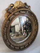 A Regency wall mirror having a circular convex plate in a carved giltwood and ball frame with a