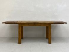 A 20th century farmhouse style extending oak dining table having a rectangular plank top with two