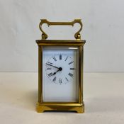 A brass carriage clock with Roman numerals on an enamelled dial. H.14.5cm