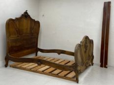 A 19th century French walnut bedstead with all-over foliate scrolling Rococo carving, to fit a