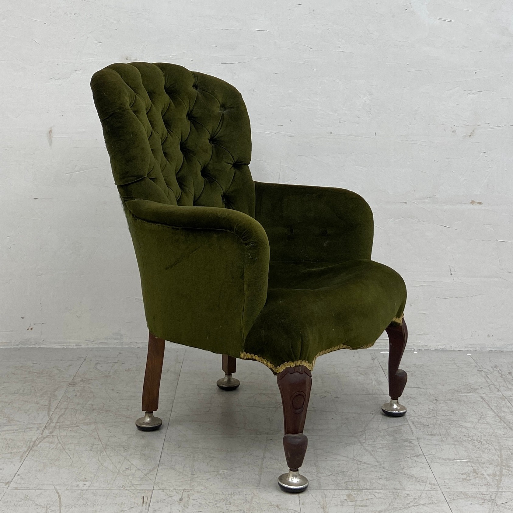 A late 19th century button-back armchair having a curved back and arms over a deep green velour