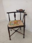 An Edwardian mahogany corner chair having a curved and marquetry inlaid back and arms with shaped