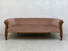 A mid 19th century oak sofa re-upholstered in foliate dusty pink raised on turned and carved