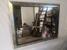 A large contemporary wall mirror having a rectangular plate in an angular silver painted and