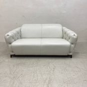 A contemporary Italian white leather two seater sofa having a curved back and deep buttoned arms