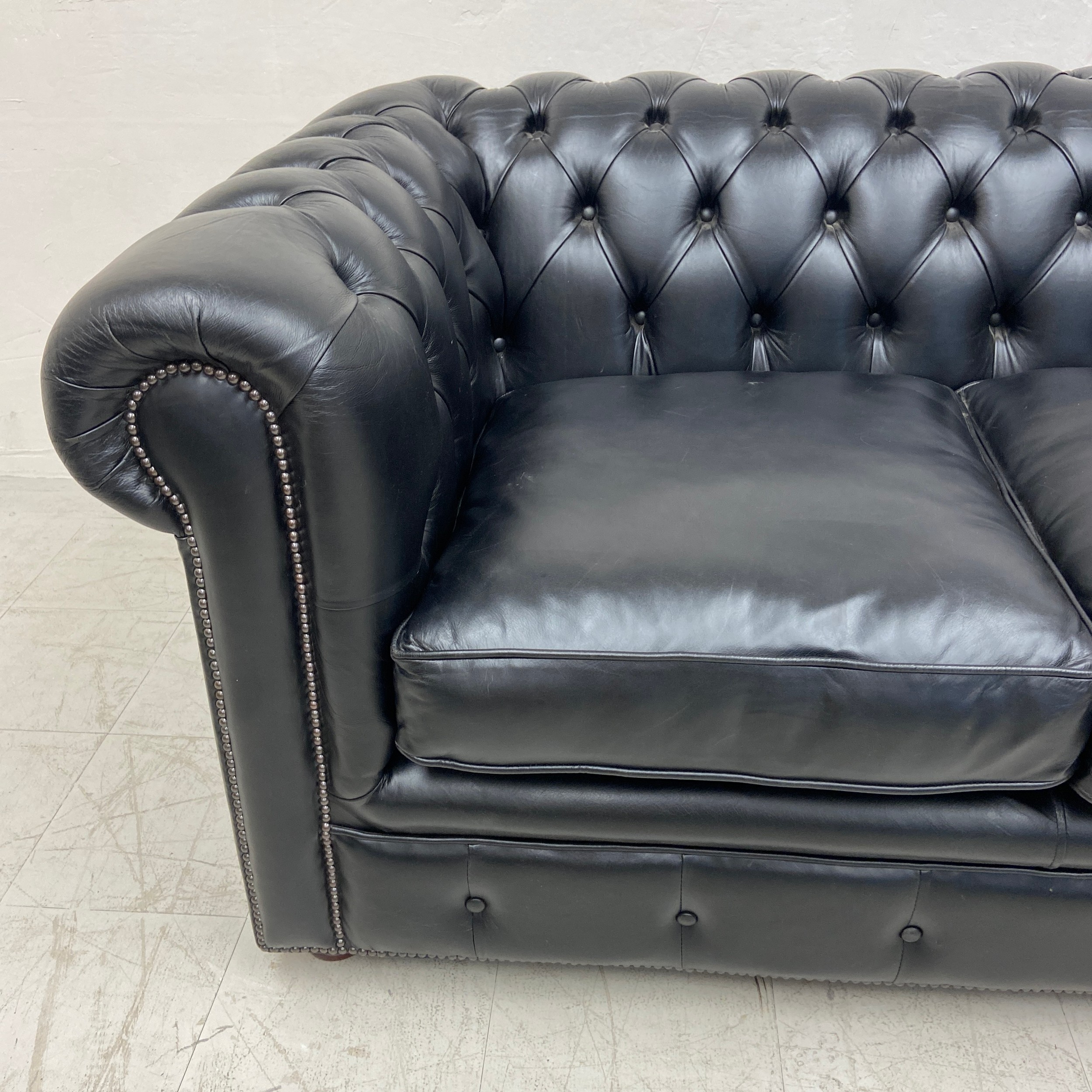 A black leather two seater Chesterfield sofa having a scrolled deep button back and arms over a - Image 3 of 3