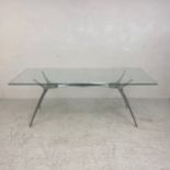 A contemporary dining table in the style of Philippe Starck with plate glass top on an aluminium