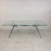 A contemporary dining table in the style of Philippe Starck with plate glass top on an aluminium