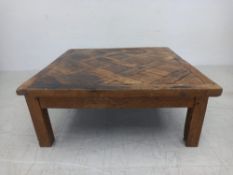 A vintage distressed pine coffee table having a square parquetry top raised on straight square