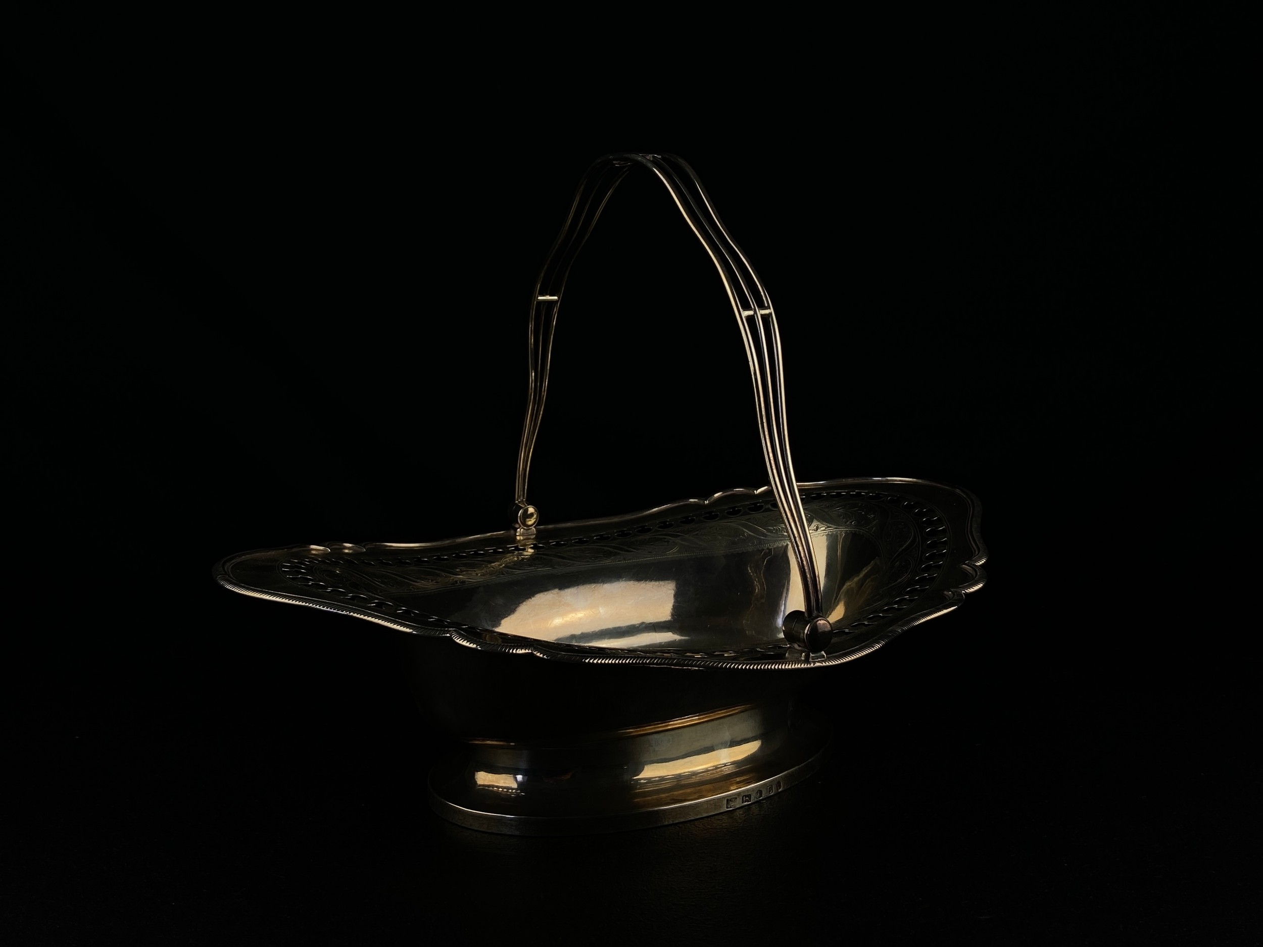 A hallmarked silver swing handled basket with pierced and engraved border on oval foot, Sheffield