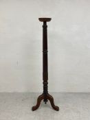A C.1900 mahogany torchere having a circular top over a tall turned and carved stem raised on shaped