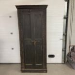 An Indian carved hall or pantry cupboard with panel doors enclosing a distressed painted interior