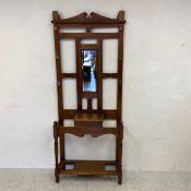 A C.1900 walnut hall stand having a shaped pediment over a small bevelled mirror in a simple