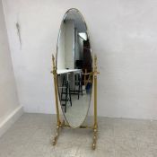 A vintage Cheval mirror having a bevelled oval plate in a gilt brass frame raised on two turned