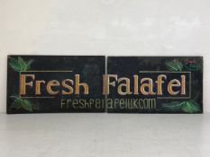 A hand painted sign, advert for 'Fresh Falafel', painted as a diptych across two large boards with
