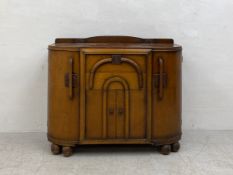 A mid 20th century Art Deco style oak side cabinet having a d-end top with a shaped gallery back