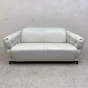 A contemporary Italian white leather two seater sofa having a curved back and deep buttoned arms