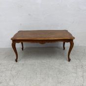 A contemporary walnut coffee table in the French 19th century style having a quarter veneered and