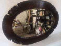 A 1950s oak wall mirror having an oval bevelled plate in a carved and beaded frame. 85X60cm