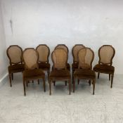 A set of eight Louis XVI style oak dining chairs each having a shaped rattan back over a cushioned