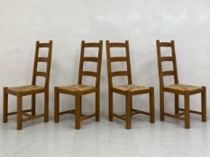 A set of four vintage oak ladderback dining chairs with rush drop-in seats raised on straight square