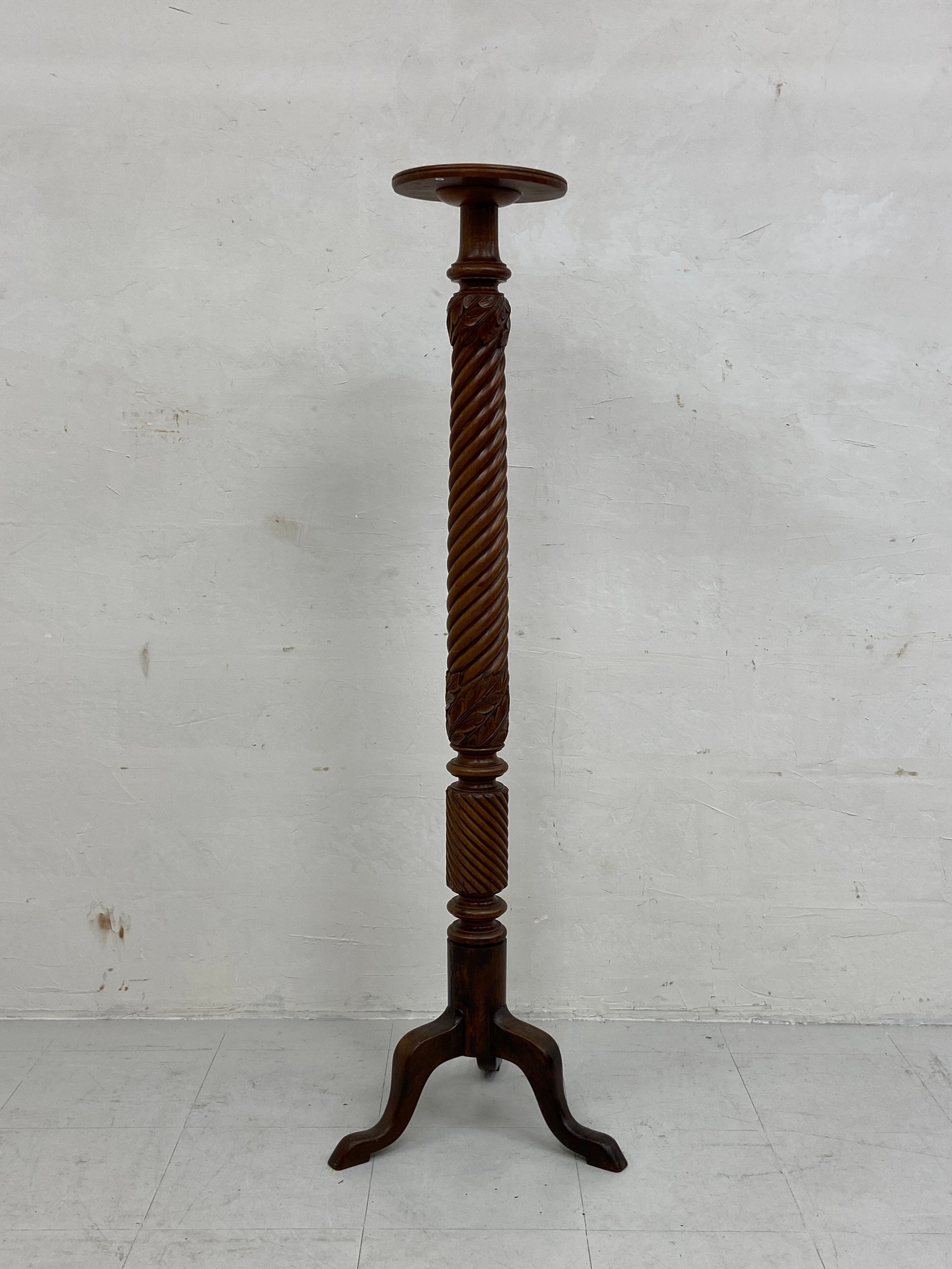 An early 20th century mahogany torchere or plant stand having a circular top over a carved twist