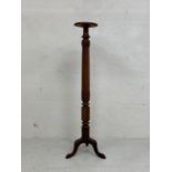 An early 20th century mahogany torchere or plant stand having a circular top over a carved twist