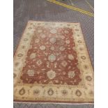 A large Ziegler style woollen carpet with flowerhead decoration across the burgundy field within