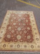 A large Ziegler style woollen carpet with flowerhead decoration across the burgundy field within