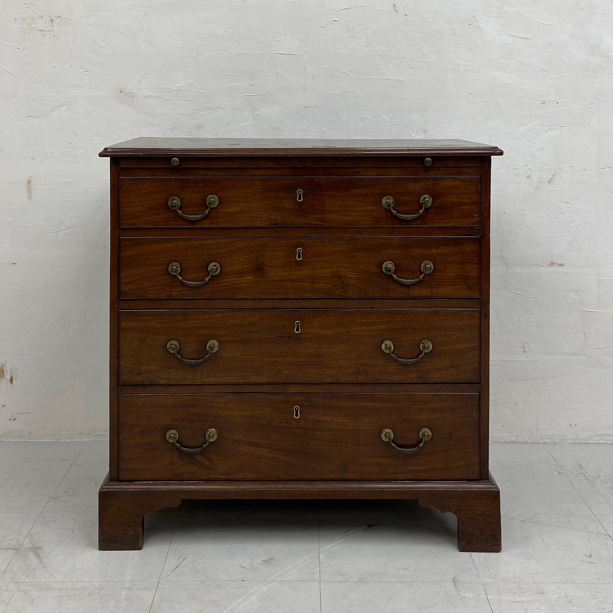 A Georgian mahogany bachelor's chest of small proportions having a thumb-moulded top with brushing