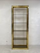 A 1970s Italian Hollywood Regency style brass, chrome and smoked glass open shelving unit having a