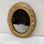 A small 19th century French wall mirror having and oval gilt gesso frame with floral motifs
