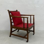 A C.1900 oak armchair having a square slatted back and open arms over a red damask upholstered