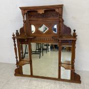 An Edwardian walnut overmantle mirror having a shaped and carved superstructure with three small