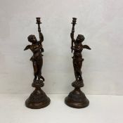 A pair of large bronze Neo-Classical candlesticks with figural cherub supports holding a flame