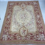 An Aubusson carpet with central bouquet within scrolling flowerhead burgundy borders. 315X240cm