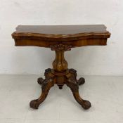 A Victorian walnut card or games table having a revolving and fold out baize lined quatrefoil top