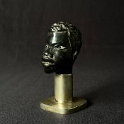 A small African carved ebony bust with glass eyes raised on a .800 silver plinth base. H.10cm